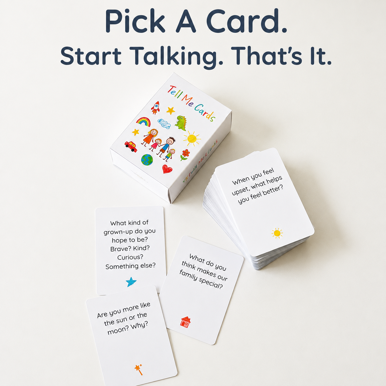 A set of white 'Tell Me Cards' shown with their colorful illustrated box and several sample cards on a light neutral background. Large text at the top reads, 'Pick A Card.